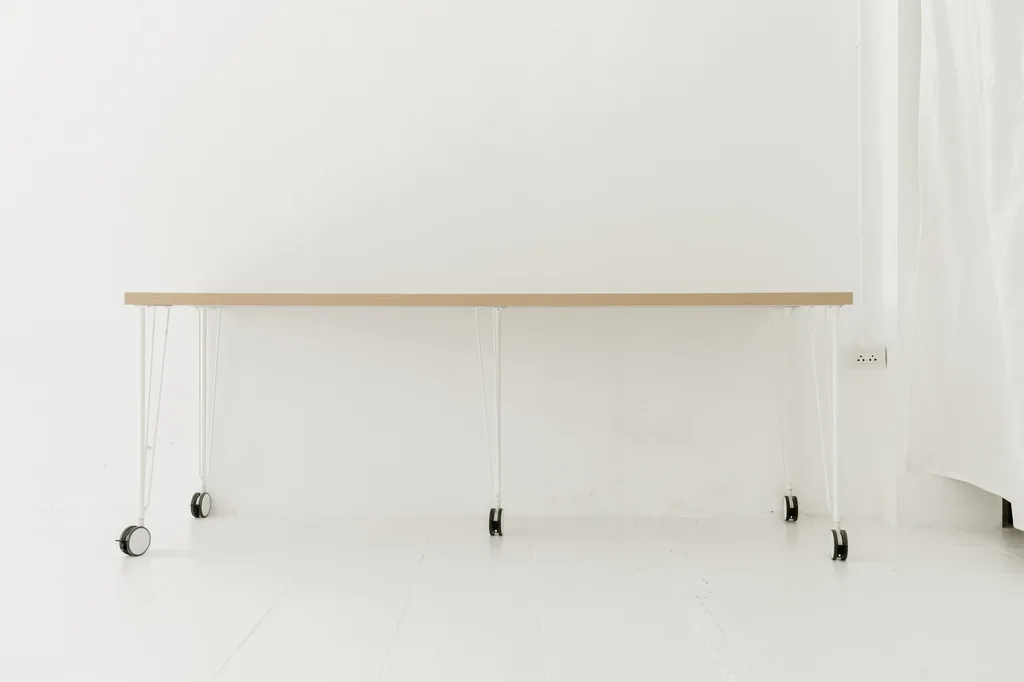 Long white table on castors in front of sheer curtains