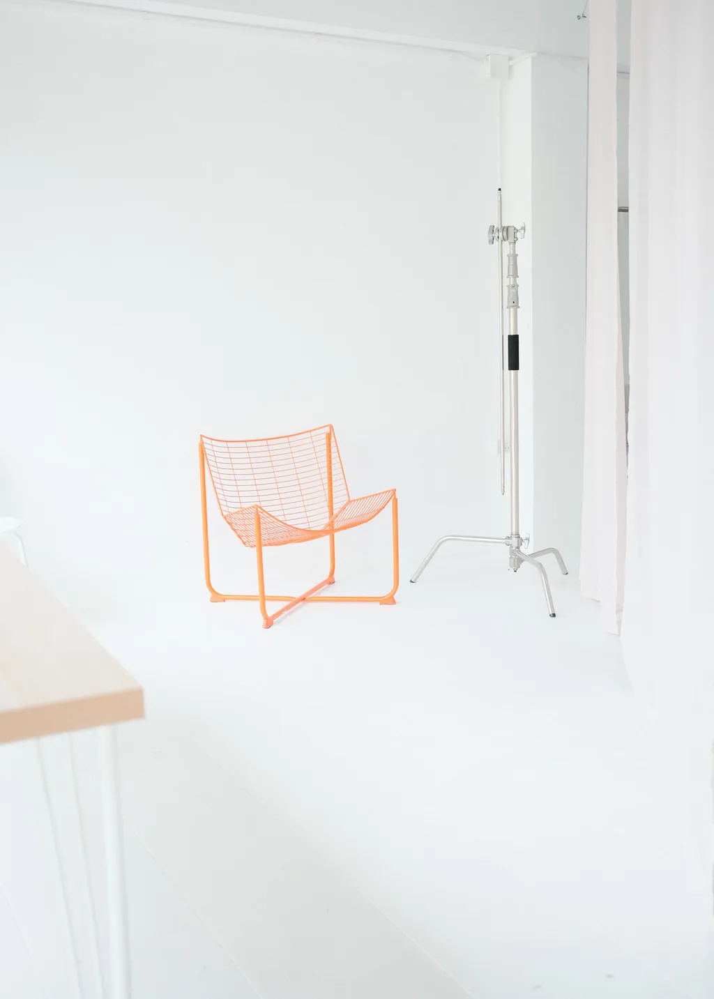 Orange wire chair among white curtains