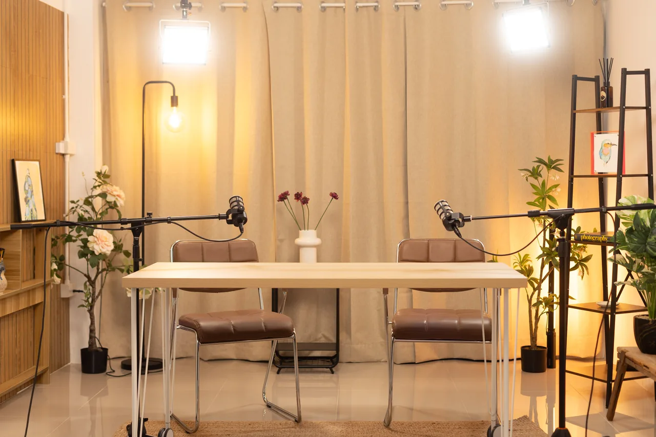 Recording desk with microphones, pendant lamps and plants set up for a shoot