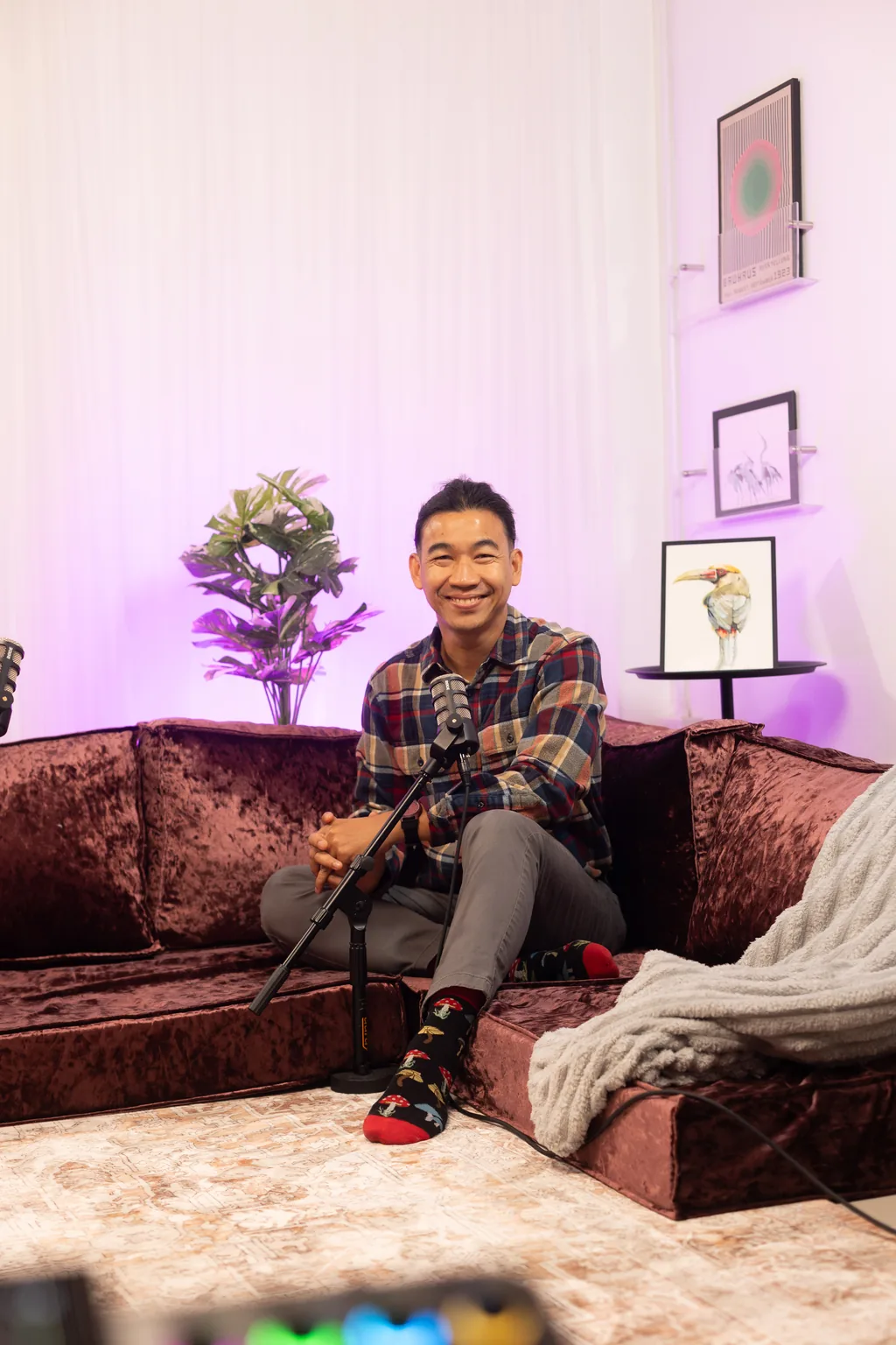 Podcast guest smiling on the velvet sofa set with a microphone