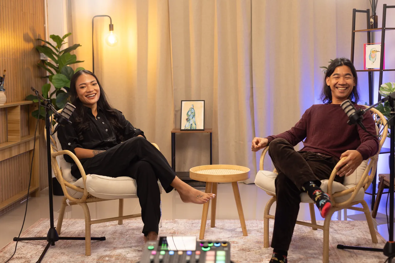 Two podcast guests laughing in wicker chairs at Studio by Char, Chiang Mai