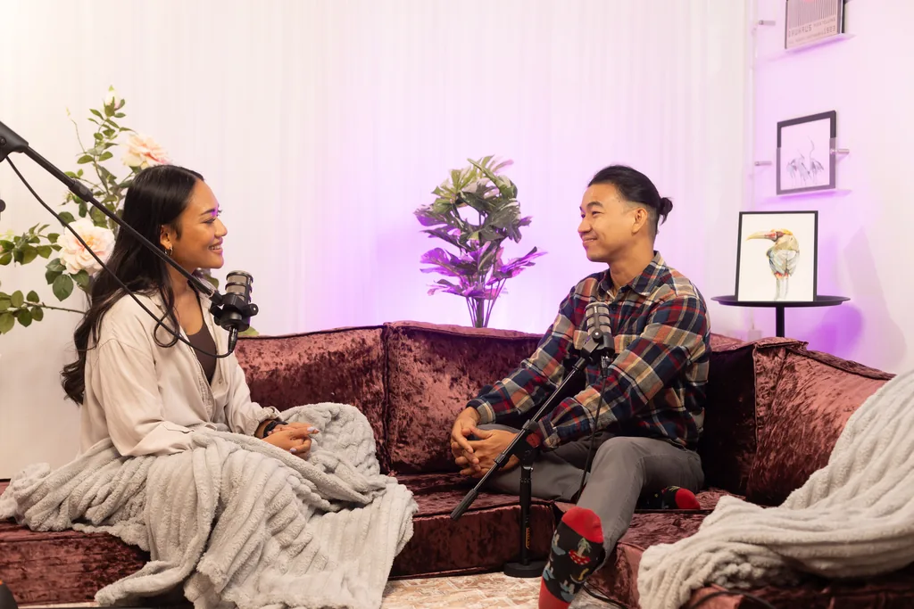 Two guests talking on the velvet sofa set under purple light