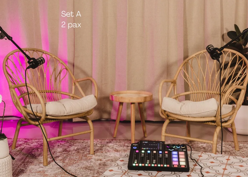 Podcast Set A: two wicker chairs, microphones and mixer under warm and pink light