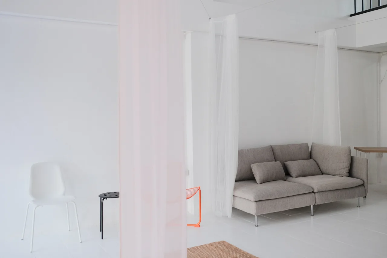 Grey sofa seen through sheer white curtains on the natural light floor