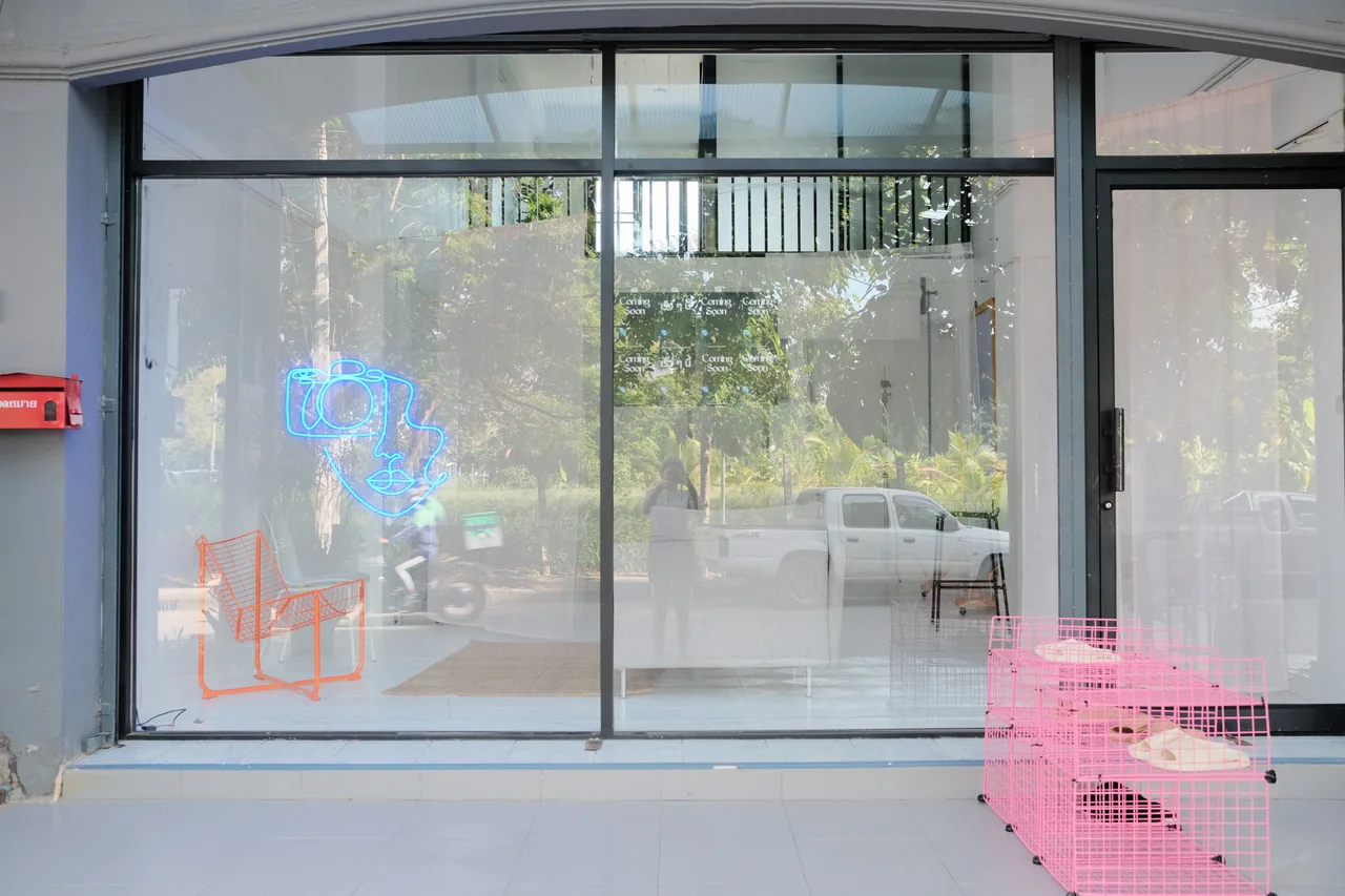The studio's glass shopfront with the neon camera logo glowing in the window