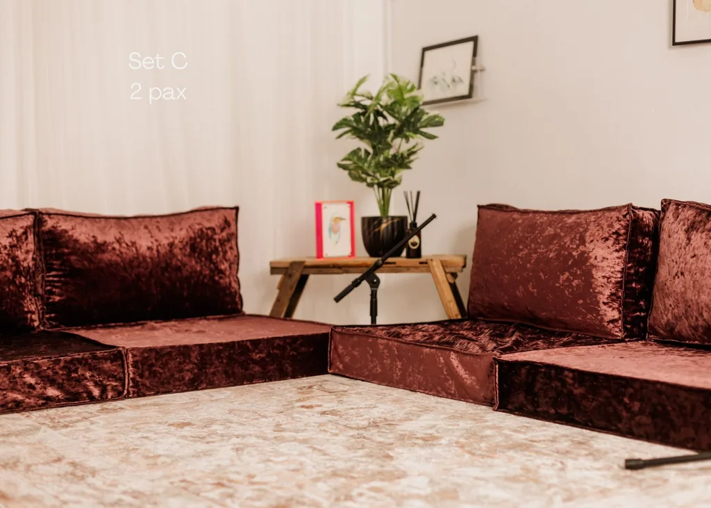 Burgundy velvet lounge sofa with cushions and a potted plant