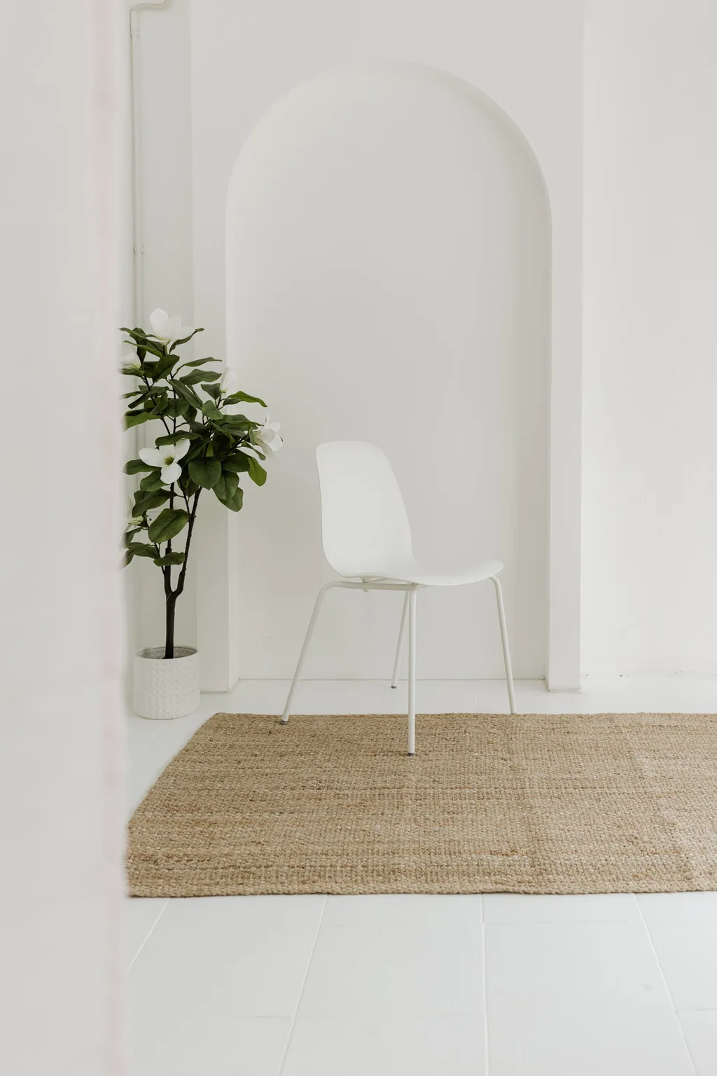 White chair, fig tree and jute rug beneath the white arch